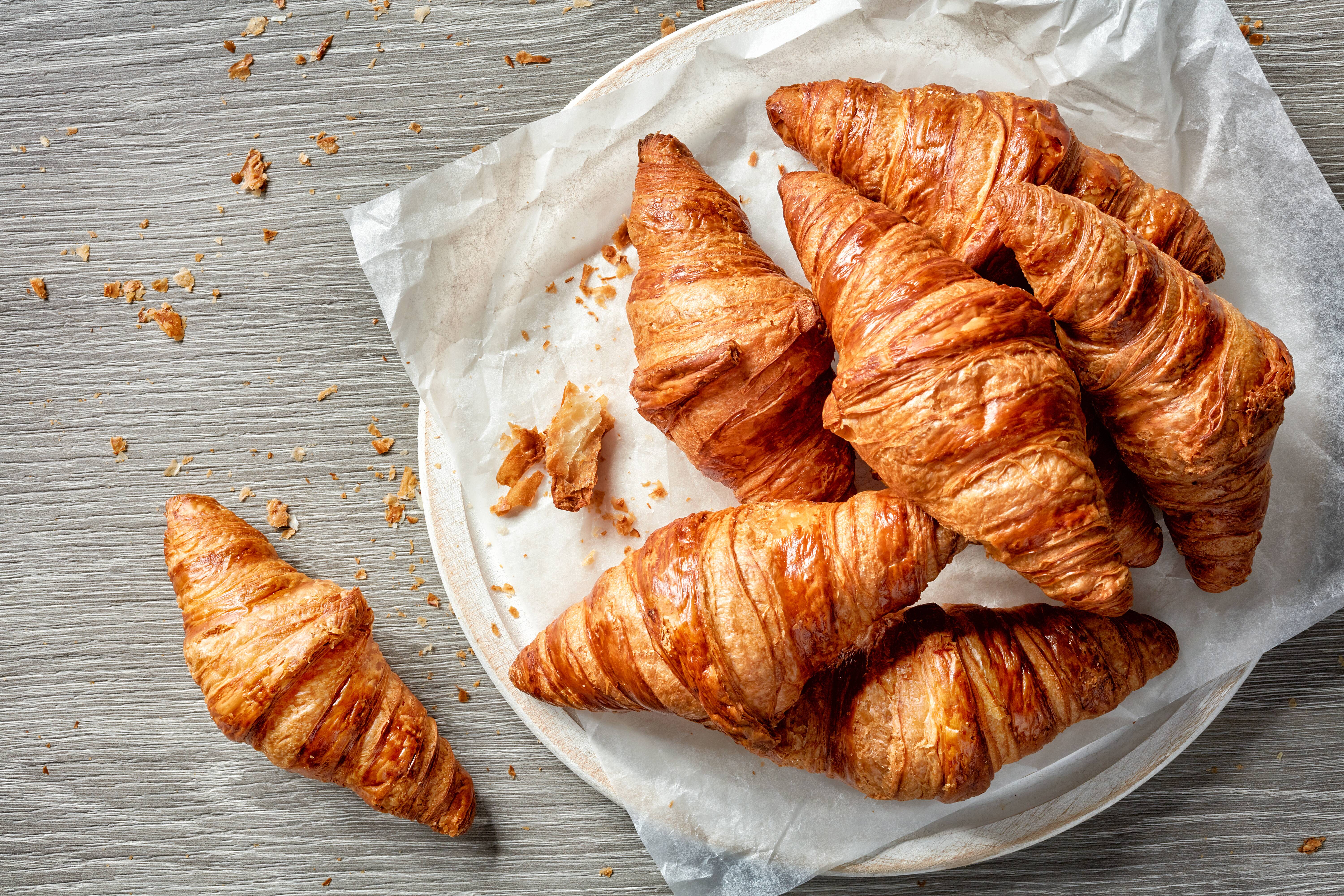 Freshly baked croissants on a plate with a croissant on the side